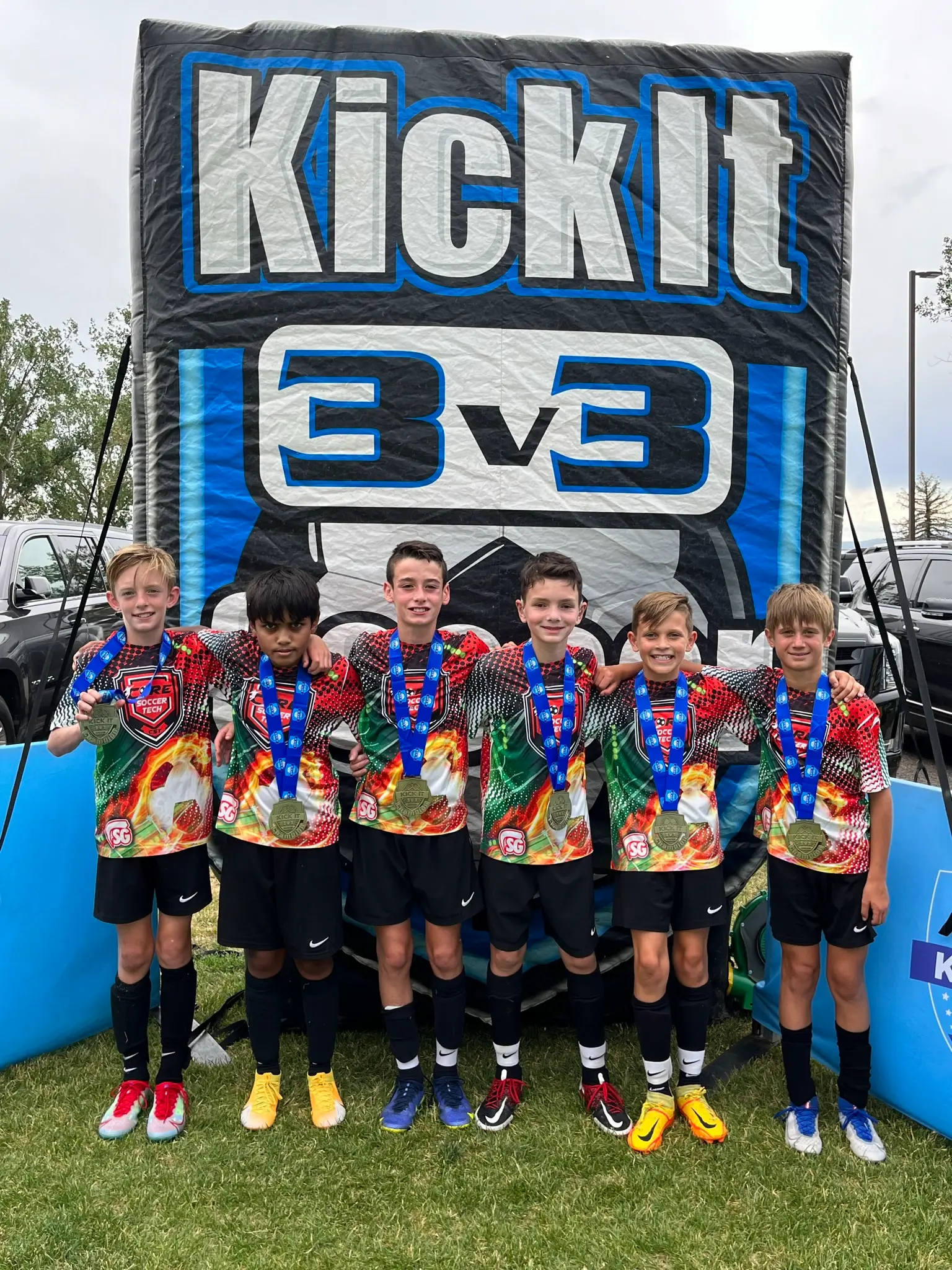 Real Colorado Academy team in colorful SG kits with gold medals in front of Kick It 3v3 banner July 2022